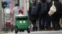 Pada acara demonstrasi hari Selasa, robot kecil berwarna hijau itu melesat melintasi trotoar dan menyeberang jalan menghindari pejalan kaki. Misinya adalah mengantarkan makanan kepada seorang demonstran yang baru saja melakukan pemesanan melalui ponsel pintarnya.