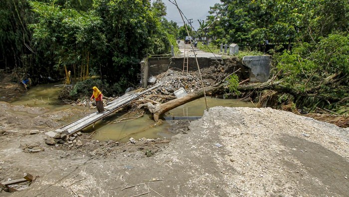 Warga melintasi lokasi bekas jembatan yang roboh di Padangan, Bojonegoro, Jawa Timur, Kamis (7/3/2024). Jembatan yang menjadi akses utama antardesa di wilayah itu roboh karena tergerus derasnya aliran sungai. ANTARA FOTO/Muhammad Mada/tom.