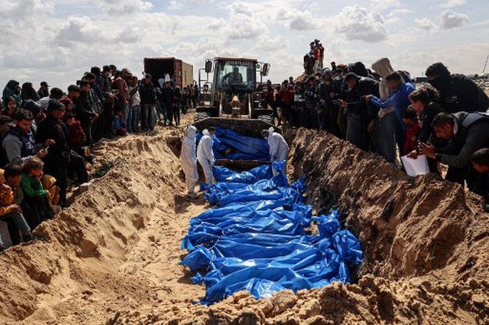 Mourners watch as medical personnel prepare the bodies of 47 Palestinians, that were taken and later released by Israel, during a mass funeral in Rafah in the southern Gaza Strip on March 7, 2024, amid ongoing battles between Israel and the militant group Hamas. Gazas Hamas-run government media office said Thursday that Israel had returned dozens of bodies that had been exhumed from graves in the besieged territory in recent weeks. (Photo by SAID KHATIB / AFP)