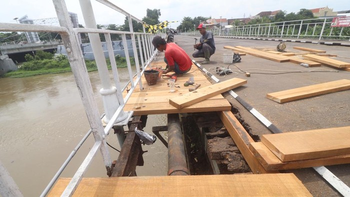 Pekerja mengganti kayu yang telah lapuk pada Jembatan Lama Kediri (Brug Over Den Brantas te Kediri) di Kota Kediri, Jawa Timur, Kamis (7/3/2024). Jembatan cagar budaya berkonstruksi besi pertama di Jawa peninggalan kolonial Belanda di atas sungai Brantas yang akan genap berusia 155 tahun pada  18 Maret 2024 tersebut menjalani perawatan dengan penggantian papan kayu dan pembersihan sampah yang tersangkut pada kaki-kaki jembatan. ANTARA FOTO/Prasetia Fauzani/tom.