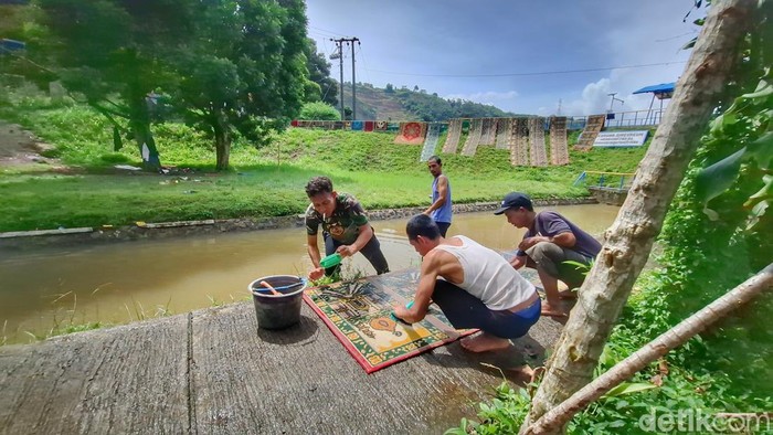 Suasana warga saat mencuci karpet masjid.