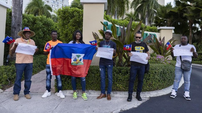 Protesters holding Haitian national flags and handmade signs with messages demanding Haiti's Prime Minister Ariel Henry resign, gather outside of the Marriott Hotel where they believe Henry is staying, in San Juan, Puerto Rico, Wednesday, March 6, 2024.  Haitian politicians started pursuing new alliances Wednesday, seeking a coalition that could lead the country out of the gang violence that has fueled lawlessness, closed the main airport and prevented Henry from returning home. (AP Photo/Alejandro Granadillo)