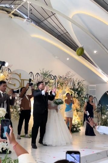 Seorang pengantin unik melemparkan durian penuh kepada para tamu undangan