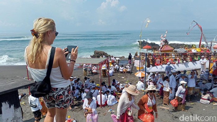 Wisatawan asing menyaksikan prosesi melasti umat Hindu Bali di Pantai Seseh, Badung, Jumat (8/3/2024). (Agus Eka Purna Negara/detikBali)