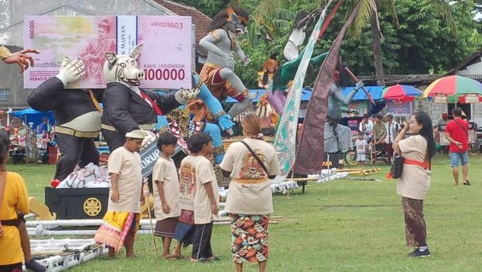 Ogoh-ogoh koruptor berbentuk tikus berperut buncit membawa segepok uang di Banyuwangi.