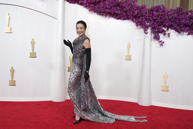 Sparkling forever. Michelle Yeoh tetap menawan di usia 61 tahun dengan gaun silver Balenciaga yang berkilauan, dipadu opera gloves dan jam tangan Richard Mille. Fun fact: gaun tersebut terbuat dari tiga gaun bekas yang dibeli Demna dari eBay. (Foto: Jordan Strauss/Invision/AP)