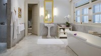 Kamar mandi dari vila ini dihias dengan lantai dan dinding marmer. Bathtub besar, shower, dan dua wastafel jadi pelengkap dari kamar mandi suite. (Capella Hotel)
