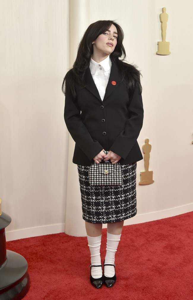 Gaya preppy jadi pilihan Billie Eilish berbusana di beberapa ajang penghargaan belakangan ini, tak terkecuali Oscars 2024. Namun penampilannya kali ini gagal membuatnya terlihat memukau. Padanan kemeja putih, blazer hitam, rok pensil tartan serta kaus kaki dan sepatu mary jane monokrom terasa monoton. Foto: Richard Shotwell/Invision/AP