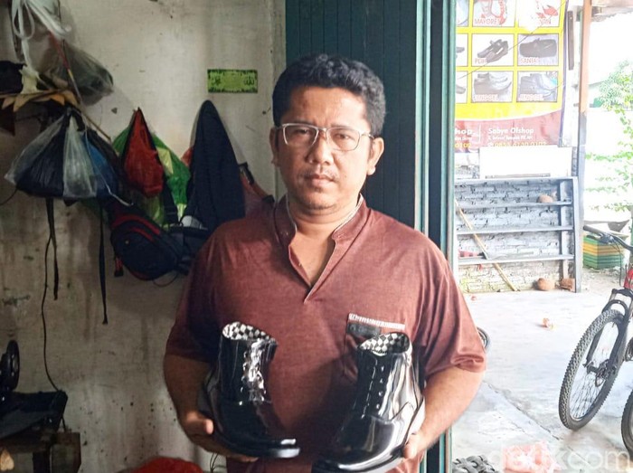 Joni Sapril Chaniago saat menunjukkan salah satu sepatu kulit yang diproduksi di tempat usahanya.  (Andika Syahputra/detikcom)
