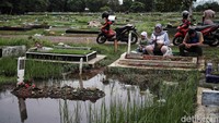 Mereka berdoa di depan makam keluarga yang kebanjiran. 
