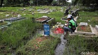 Dua orang warga tampak khusyuk berdoa di depan makam keluarga. 