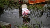Bunga yang harusnya ditabur digantungkan di papan nisan. Hal itu dilakukan karena banjir merendam makam. 