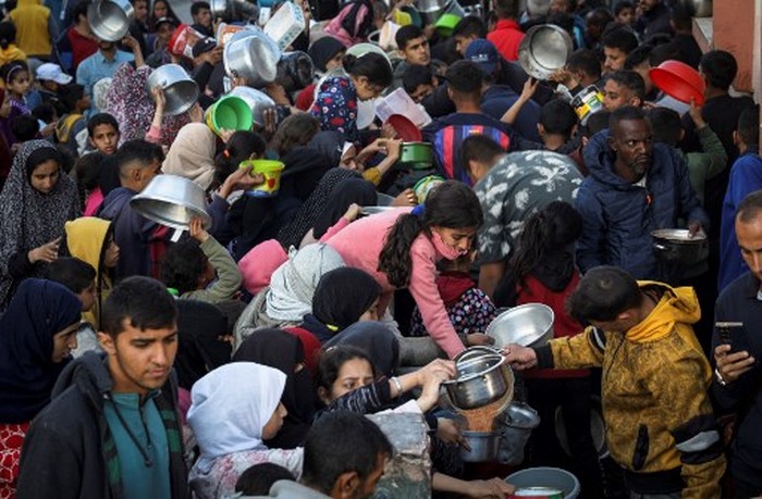 The Palestinian Al-Naji family eats an iftar meal, the breaking of fast, amidst the ruins of their family house, on the first day of the Muslim holy fasting month of Ramadan, in Deir el-Balah in the central Gaza Strip on March 11, 2024, amid ongoing battles between Israel and the militant group Hamas. (Photo by AFP)