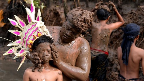 Sejumlah warga yang tubuhnya dilumuri lumpur berjalan berkeliling kampung saat mengikuti tradisi Mebuug-Buugan di kawasan Kedonganan, Badung, Bali, Selasa (12/3/2024). Tradisi Mebuug-Buugan atau mandi lumpur itu dilakukan ratusan warga setempat sebagai simbol untuk menghilangkan kekotoran dan hal-hal negatif setelah Hari Raya Nyepi Tahun Saka 1946. ANTARA FOTO/Fikri Yusuf/aww.