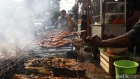Seorang pedagang tengah membakar ikan untuk sajian makan setelah buka puasa.