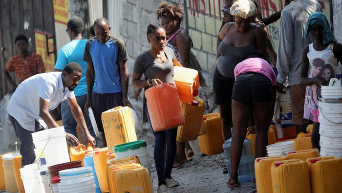 People wait along a street to collect water in buckets and containers after Haiti's Prime Minister Ariel Henry pledged to step down following months of escalating gang violence, in Port-au-Prince, Haiti March 12, 2024. REUTERS/Ralph Tedy Erol