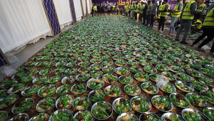 Families eat pre-dawn meal or 'Sehri' to start their fasting during the Muslim's holy fasting month of Ramadan, at a free meal distribution point run by a charity group, in Karachi, Pakistan, Wednesday, March 13, 2024. (AP Photo/Fareed Khan)