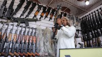 Pedagang senjata Qaed Elaiyan berdiri di tokonya di Sanaa, Yaman.  