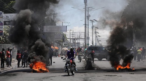 Motorists pass by a burning barricade during a protest as the government said it would extend a state of emergency for another month after an escalation in violence from gangs seeking to oust the Prime Minister Ariel Henry, in Port-au-Prince, Haiti, March 7, 2024. REUTERS/Ralph Tedy Erol