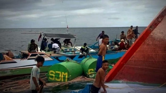 Warga membantu proses evakuasi beberapa kru KM Dewi Jaya II yang selamat setelah terombang ambing di perairan, Selasa (12/3).