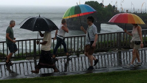 Wisatawan berjalan di dekat papan larangan di objek wisata Tanah Lot, Tabanan, Bali, Kamis (14/3/2024). Badan Meteorologi, Klimatologi, dan Geofisika (BMKG) Wilayah III Denpasar memprediksi terjadinya cuaca ekstrem di wilayah Bali selama tiga hari pada 14-16 Maret 2024 yang merupakan dampak dari terbentuknya bibit siklon tropis 91S dan 94S di wilayah Indonesia. ANTARA FOTO/Nyoman Hendra Wibowo/rwa.