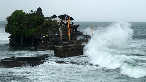 Wisatawan berjalan di dekat papan larangan di objek wisata Tanah Lot, Tabanan, Bali, Kamis (14/3/2024). Badan Meteorologi, Klimatologi, dan Geofisika (BMKG) Wilayah III Denpasar memprediksi terjadinya cuaca ekstrem di wilayah Bali selama tiga hari pada 14-16 Maret 2024 yang merupakan dampak dari terbentuknya bibit siklon tropis 91S dan 94S di wilayah Indonesia. ANTARA FOTO/Nyoman Hendra Wibowo/rwa.