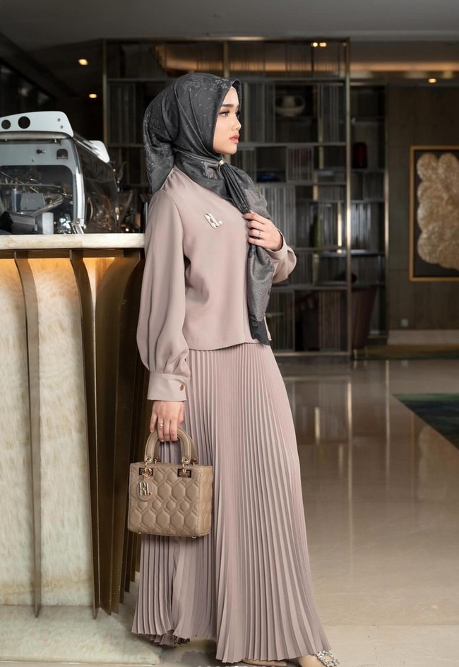 Tampil beda berhijab, gaya Fuji yang satu ini terlihat bak ibu-ibu pejabat Ia memadukan blouse lengan panjang dengan rok plisket dan tas berwarna senada. Untuk melengkapinya Fuji mengenakan hijab bermotif warna abu-abu. Foto: Instagram/@fuji_an