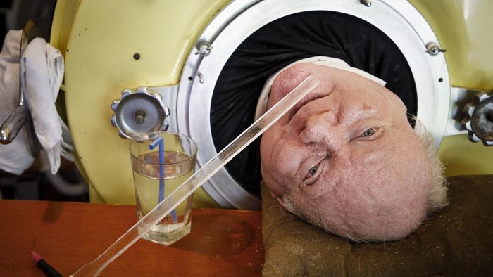 FILE -  In this Friday, April 27, 2018 photo, caregiver and friend Kathryn Gaines washes the face of attorney Paul Alexander beside his iron lung at his home in Dallas. Alexander died Monday, March 11, 2024 at a Dallas hospital, said Daniel Spinks, a longtime friend. He said Alexander had recently been hospitalized after being diagnosed with COVID-19 but did not know the cause of death.  (Smiley N. Pool/The Dallas Morning News via AP)