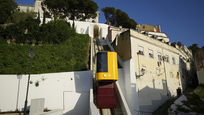 A passenger looks out from the just inaugurated funicular that connects the top of the Graca hill neighborhood with downtown Lisbon, Wednesday, March 13, 2024. The new funicular that can carry fourteen passengers joins three others operating in different Lisbon hills since the late 19th century. (AP Photo/Armando Franca)