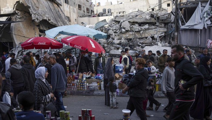 Palestinians buy food at a local market next to a destroyed residential building by the Israeli airstrikes, during the Muslim holy month of Ramadan, in Rafah, Gaza Strip, Thursday, March 14, 2024. (AP Photo/Fatima Shbair)