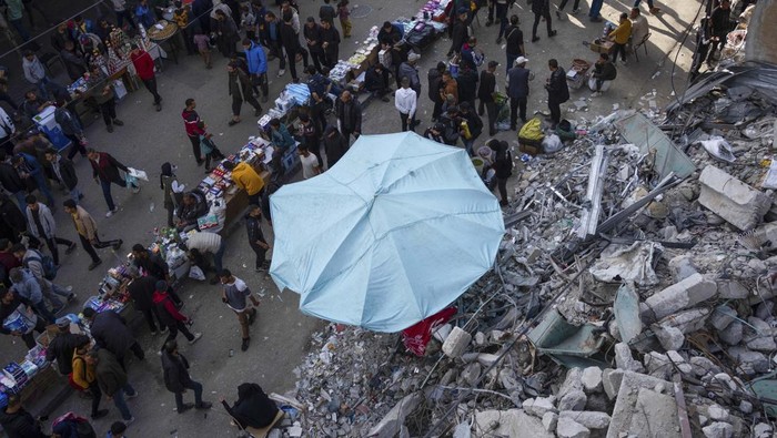 Palestinians buy food at a local market next to a destroyed residential building by the Israeli airstrikes, during the Muslim holy month of Ramadan, in Rafah, Gaza Strip, Thursday, March 14, 2024. (AP Photo/Fatima Shbair)