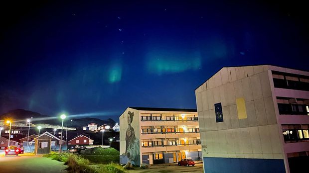 FILE PHOTO: The Aurora Borealis (Northern Lights) is seen behind a building with social housings with a mural in Nuuk, Greenland, September 17, 2021. REUTERS/Hannibal Hanschke/File Photo
