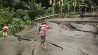 Dua anak melewati jalan rusak di Oebufu, Kecamatan Oebobo, Kota Kupang, NTT, Kamis (14/3/2024).