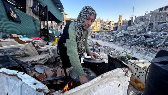 Palestinian members of Al-Khlout family wait to break their fast on the rubble of their house which was destroyed during Israel's military offensive, during the holy month of Ramadan, as the conflict between Israel and Hamas continues, in Beit Lahia in the northern Gaza Strip, March 13, 2024. REUTERS/Mahmoud Issa