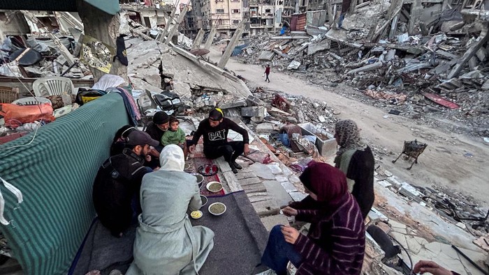Palestinian members of Al-Khlout family wait to break their fast on the rubble of their house which was destroyed during Israel's military offensive, during the holy month of Ramadan, as the conflict between Israel and Hamas continues, in Beit Lahia in the northern Gaza Strip, March 13, 2024. REUTERS/Mahmoud Issa