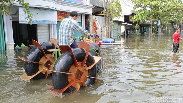 Tasin (51) tampak menjajal sepeda air buatannya di tengah banjir di depan rumahnya di Jalan Raya Kaligawe, Semarang, Jumat (15/3/2024).