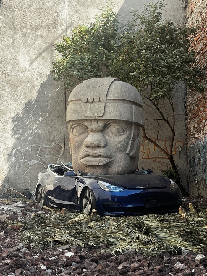A replica of a colossal Olmec head crushing a Tesla car, an intervention by Mexican artist Chavis Marmol, is pictured at a vacant lot in Mexico City, Mexico March 14, 2024. REUTERS/Raquel Cunha NO RESALES. NO ARCHIVES