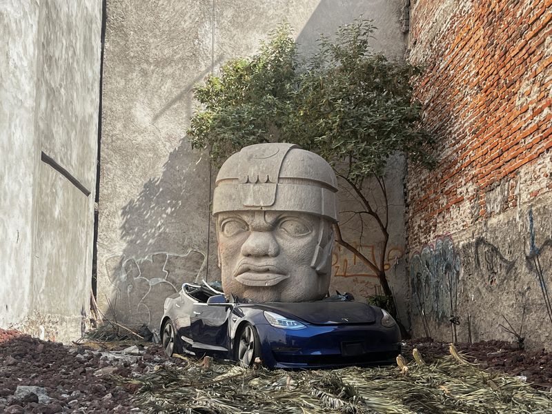 A replica of a colossal Olmec head crushing a Tesla car, an intervention by Mexican artist Chavis Marmol, is pictured at a vacant lot in Mexico City, Mexico March 14, 2024. REUTERS/Raquel Cunha NO RESALES. NO ARCHIVES