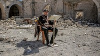 Seorang warga Palestina membacakan Al-Quran di atas puing-puing Masjid Agung Omar, yang hancur akibat pemboman Israel, selama Ramadhan di Jalur Gaza pada 12 Maret 2024. Omar Qattaa/Anadolu via Getty Images.