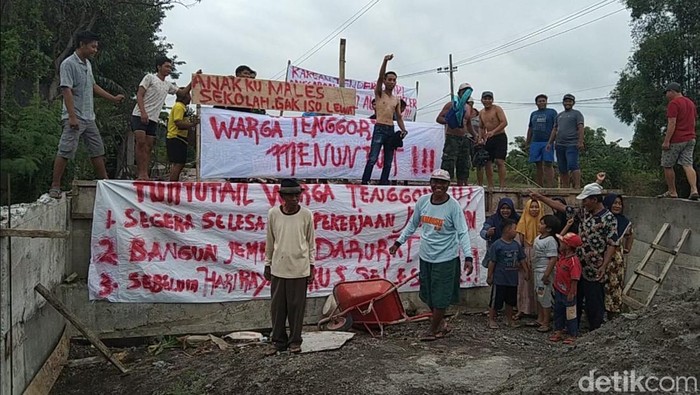Warga memasang spanduk demo di lokasi pembangunan jembatan.