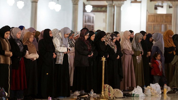 Ramadan crescent moon appears in the sky beside Al Azhar mosque minaret as muslim worshippers perform evening prayers called 