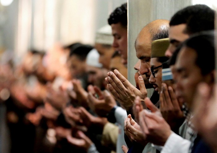 Ramadan crescent moon appears in the sky beside Al Azhar mosque minaret as muslim worshippers perform evening prayers called 