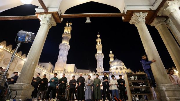 Ramadan crescent moon appears in the sky beside Al Azhar mosque minaret as muslim worshippers perform evening prayers called 