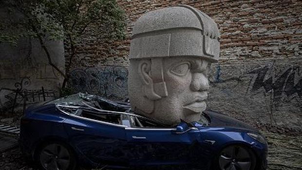 An artwork by artist Chavis Marmol, a Tesla 3 car crushed by a nine-ton Olmec-inspired head, is pictured in Mexico City on March 13, 2024. A 42-year-old sculptor, Marmol has never owned a car and travels by bicycle, but he had the luxury of unloading with cranes the nine-ton effigy on a blue Tesla 3, one of the electric models manufactured by US billionaire Elon Musk's company. (Photo by CARL DE SOUZA / AFP) / RESTRICTED TO EDITORIAL USE - MANDATORY MENTION OF THE ARTIST UPON PUBLICATION - TO ILLUSTRATE THE EVENT AS SPECIFIED IN THE CAPTION