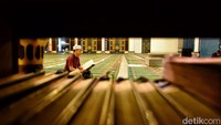 Seorang warga tengah fokus membawa Al-Quran di salah satu sudut Masjid Al Akbar Surabaya.