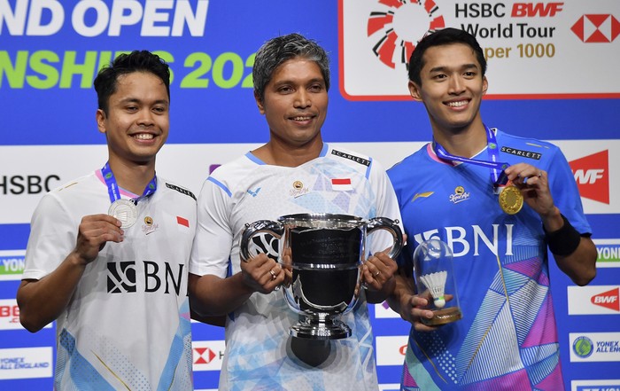 Indonesias Anthony Sinisuka Ginting, left, and Indonesias Jonatan Christie, right pose with coach Irwansyah, centre, after the mens singles final match of the All England Open Badminton Championships at the Utilita Arena in Birmingham, England, Sunday, March 17, 2024. (AP Photo/Rui Vieira)