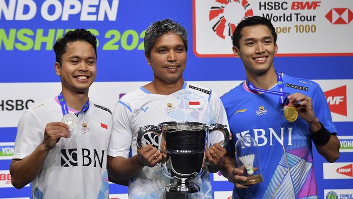 Indonesias Anthony Sinisuka Ginting, left, and Indonesias Jonatan Christie, right pose with coach Irwansyah, centre, after the mens singles final match of the All England Open Badminton Championships at the Utilita Arena in Birmingham, England, Sunday, March 17, 2024. (AP Photo/Rui Vieira)