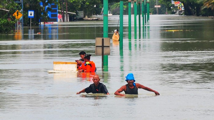 Warga melintasi jalan Pantura yang terendam banjir di Karanganyar, Demak, Jawa Tengah, Minggu (17/3/2024). Banjir yang disebabkan jebolnya tanggul Sungai Wulan pascahujan deras dari wilayah hulu itu merendam jalan nasional jalur Semarang-Surabaya, sementara arus lalu-lintas dialihkan ke jalur alternatif melalui Kabupaten Jepara dan Grobogan. ANTARA FOTO/Yusuf Nugroho/foc.