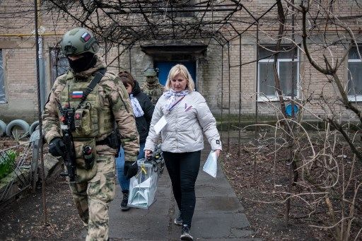 Members of a local election commission, accompanied by servicemen, visit voters during early voting in Russia's presidential election in Donetsk, Russian-controlled Ukraine, amid the Russia-Ukraine conflict on March 14, 2024. (Photo by STRINGER / AFP)