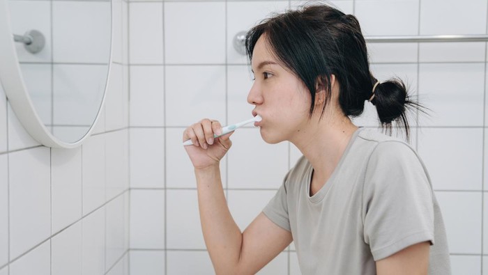 Asian Woman Cleaning Teeth With Toothbrush And Paste Doing Daily Oral Hygiene Routine In Bathroom At Home. Closeup Of Female Brushing Teeth.
